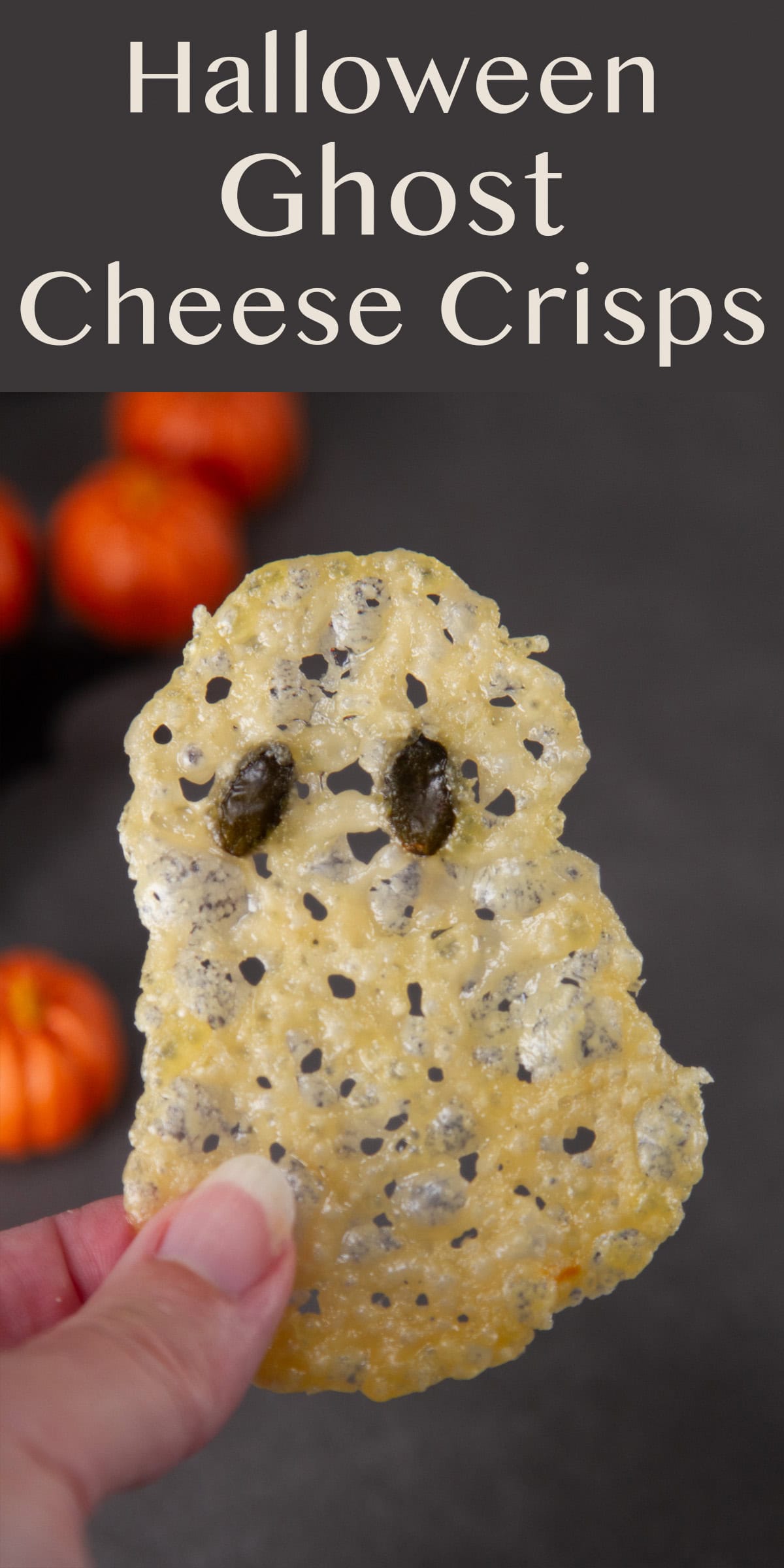 a hand holding a cheese crisp shaped like a ghost.