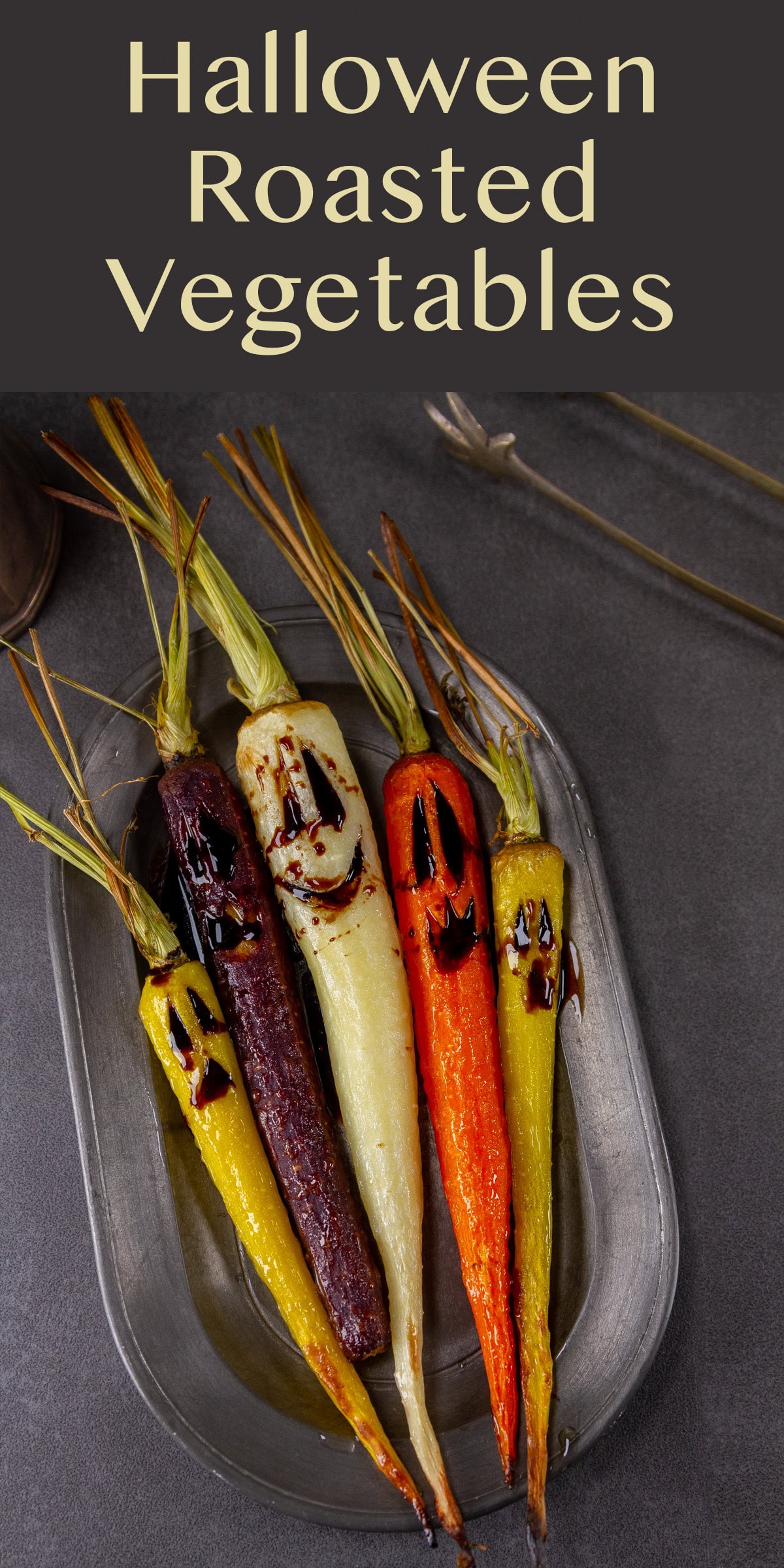 roasted carrots with Halloween faces on a pewter serving dish.