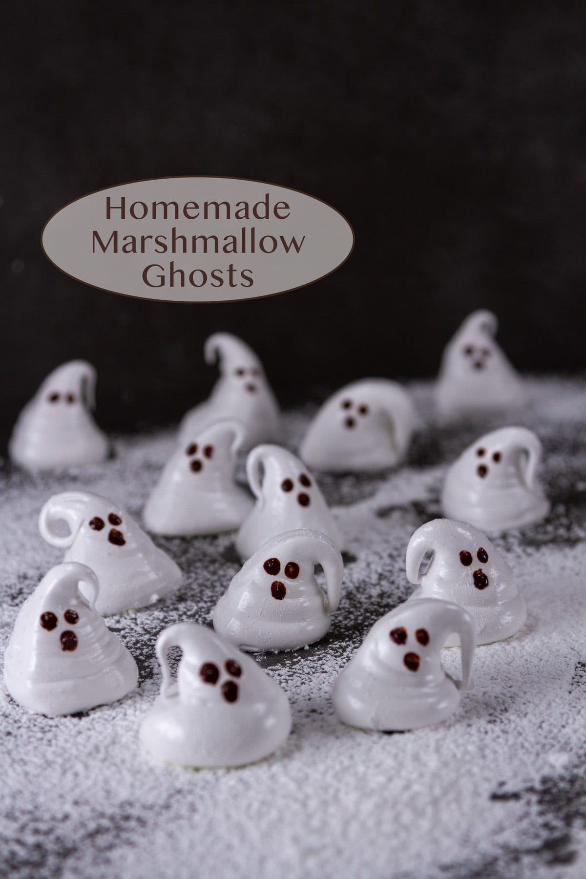 marshmallow ghosts on powdered sugar on a black background.
