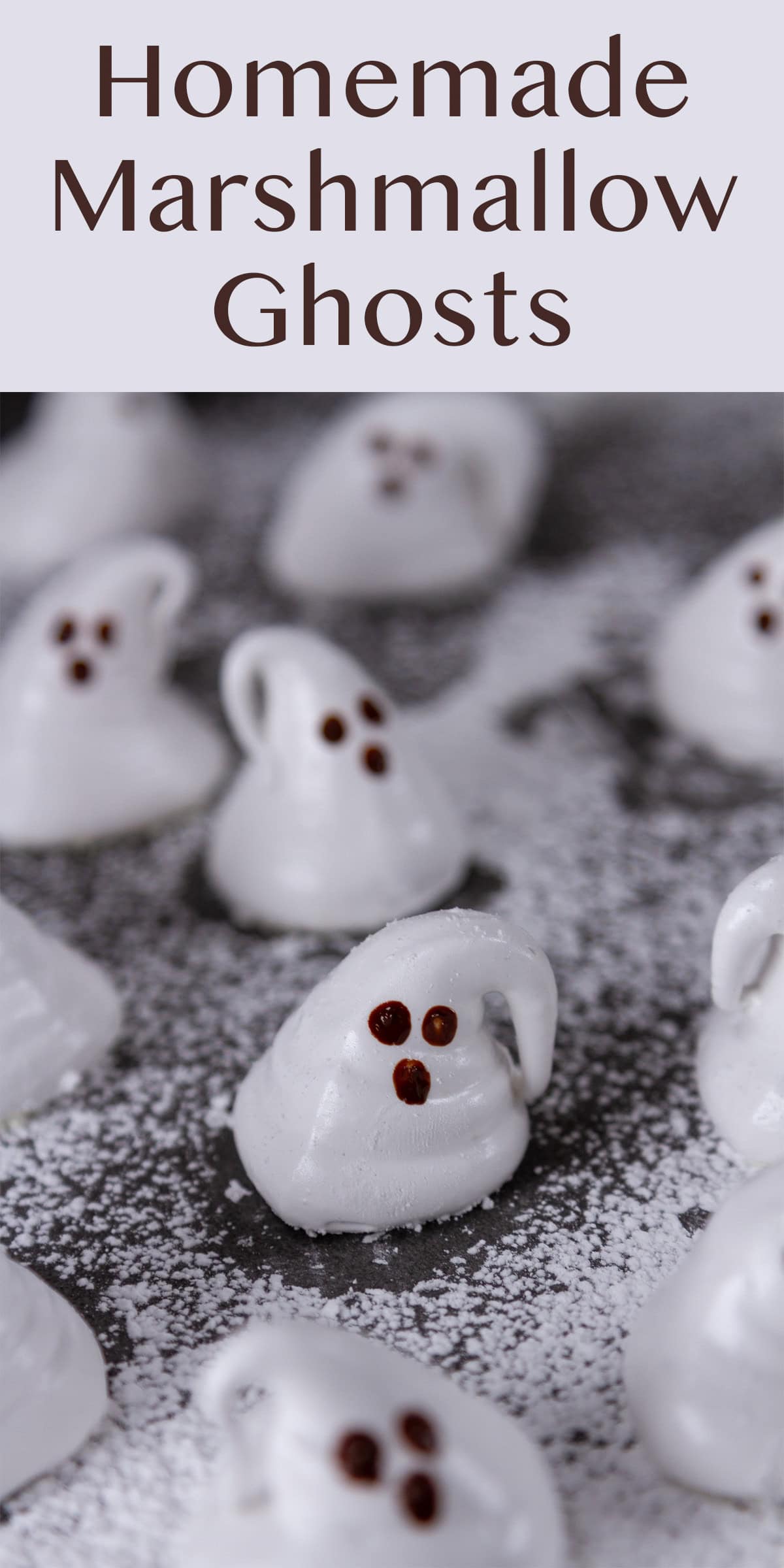 marshmallows shaped like ghosts on a black background covered with powdered sugar.