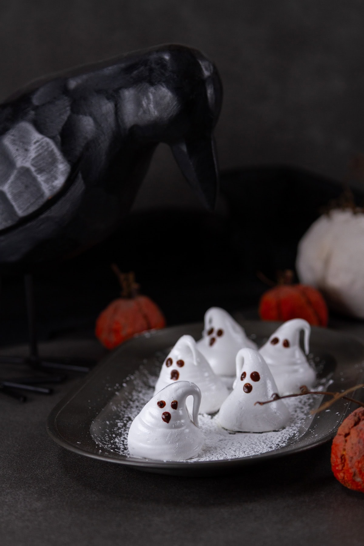 a pewter tray with marshmallow ghosts on it being looked at by a crow.