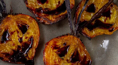 square crop of roasted beets with jack-o-latern faces.