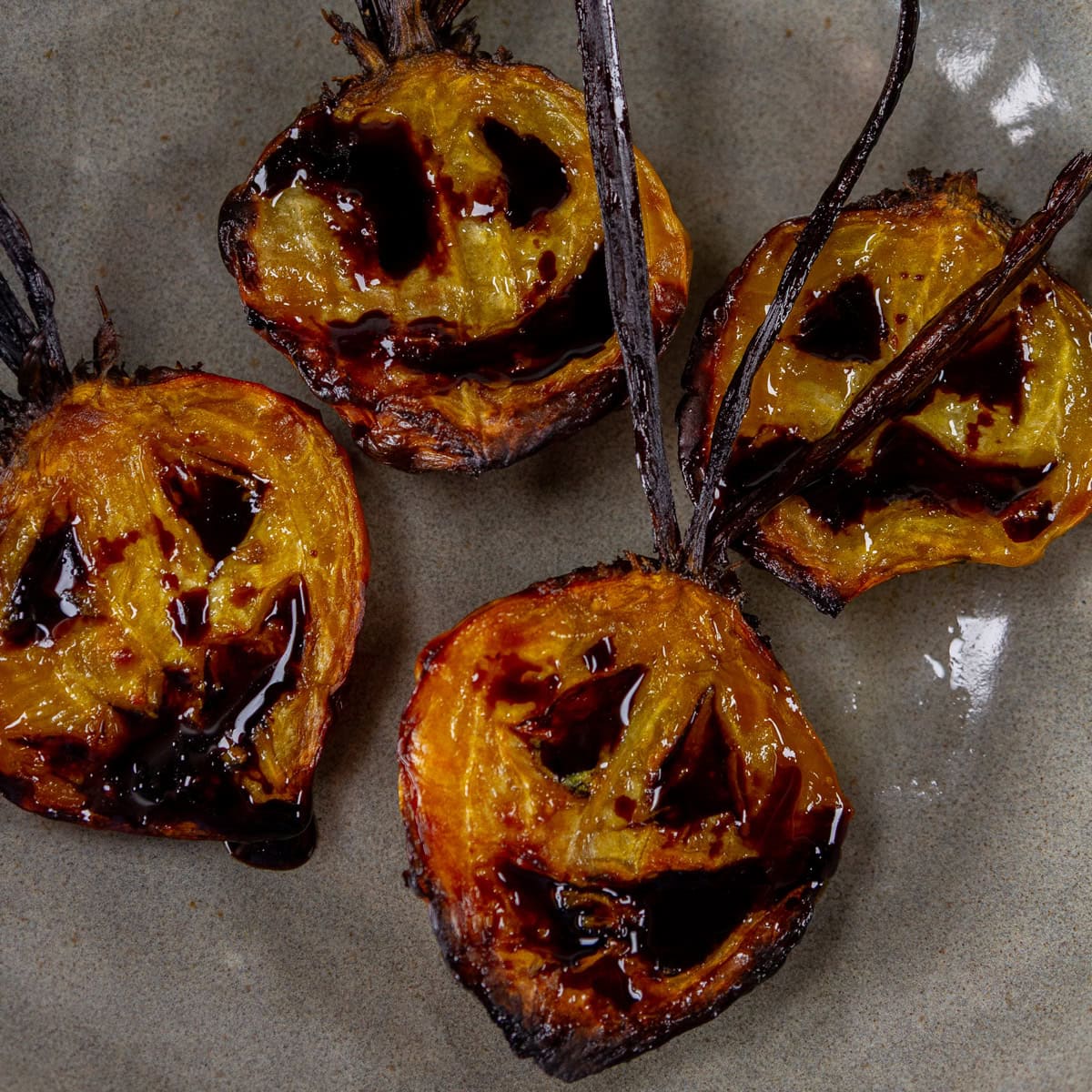 square crop of roasted beets with jack-o-latern faces.